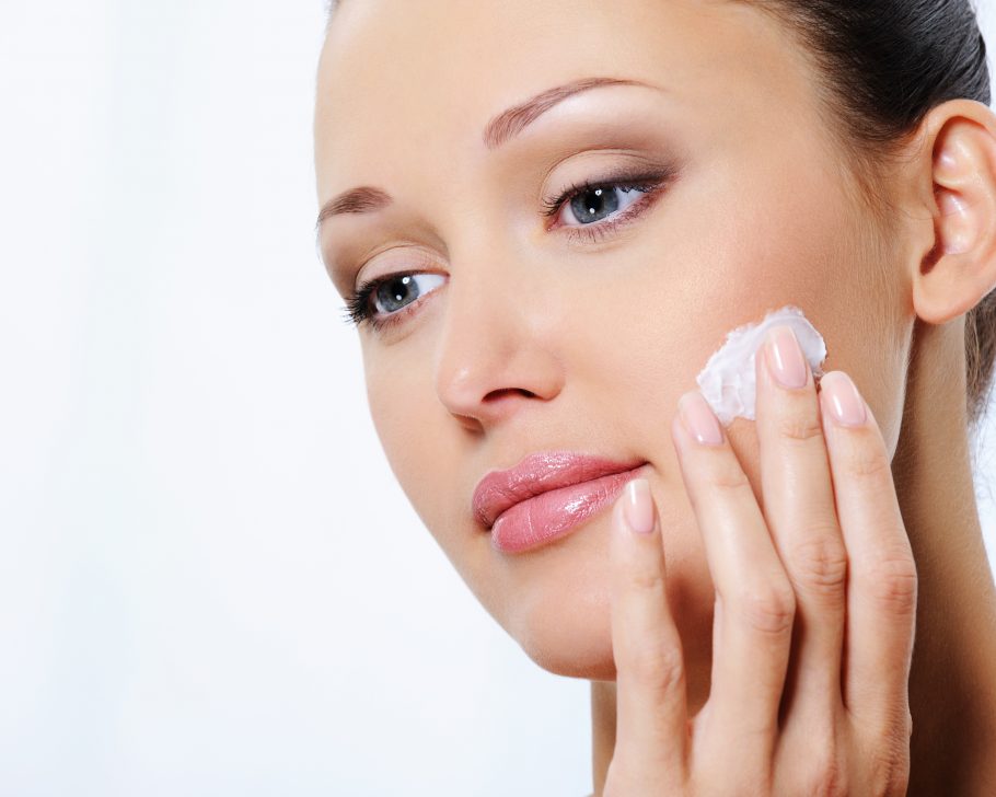 Young beautiful woman caring of her face with moisturizer cream